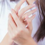 woman in white shirt covering her face with her hand