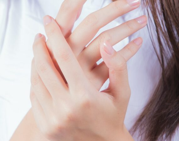 woman in white shirt covering her face with her hand