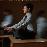 man in white and blue pinstripe dress shirt sitting on brown wooden table