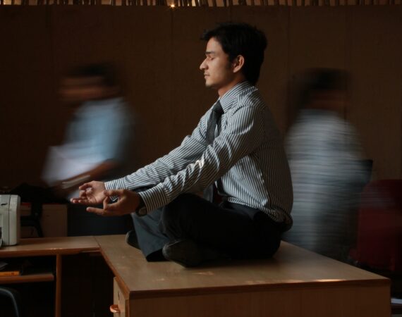 man in white and blue pinstripe dress shirt sitting on brown wooden table