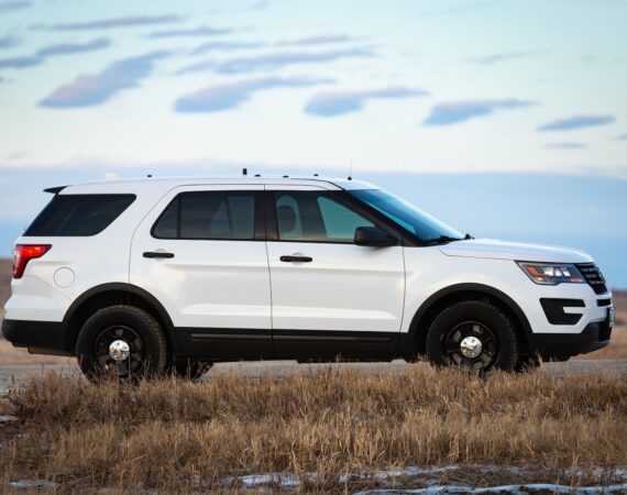 white suv on brown grass field under white clouds during daytime